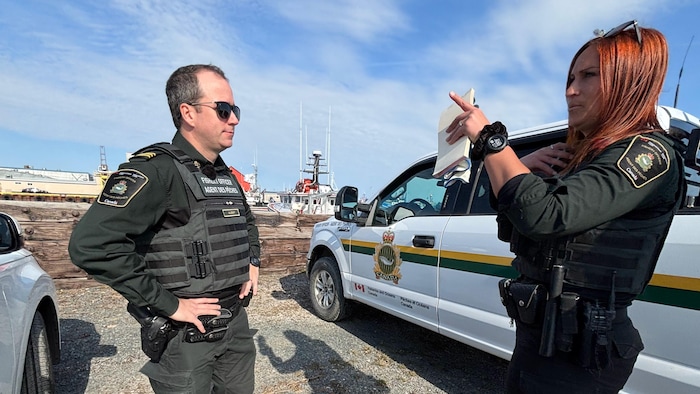 Deux agents des pêches qui discutent sur la terre ferme.