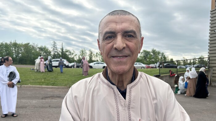 Un homme avec les bras croisés sourit.