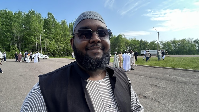 Un homme sourit avec des lunettes de soleil aux yeux.