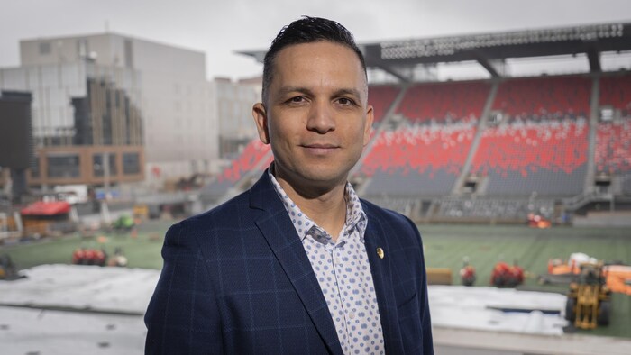 Un homme pose devant les gradins d'un stade.