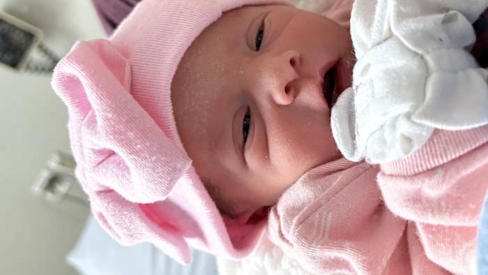 La petite Amayah porte un pyjama rose, un petit chapeau et des petites mitaines de nouveau-né.