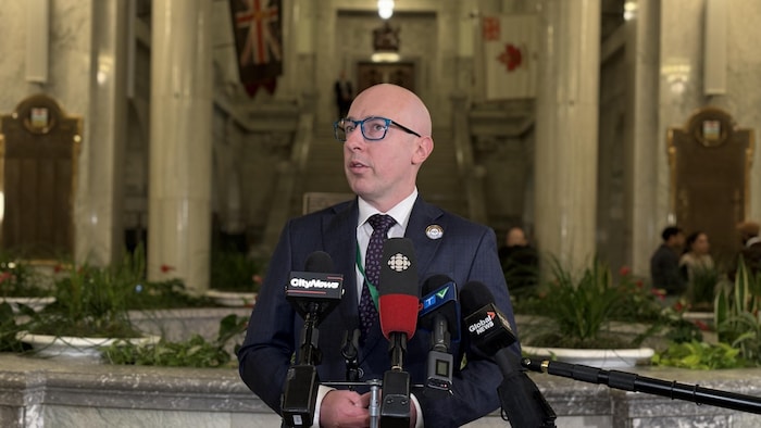Le maire d'Edmonton parle devant plusieurs micros dans la rotonde de l'Assemblée législative.