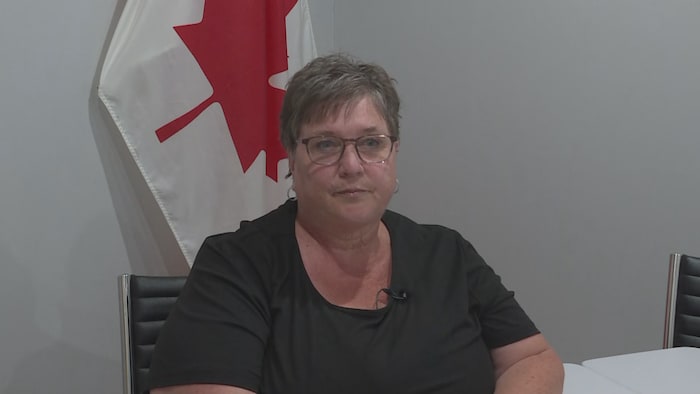 Une femme assise devant un drapeau du Canada