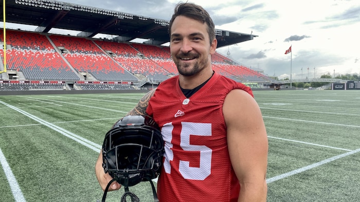 Un joueur de football pose avec son casque et son uniforme d'entraînement