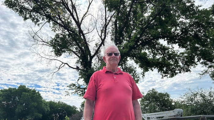 Jim Hunter se tient devant l'arbre sur le point d'être déraciné.