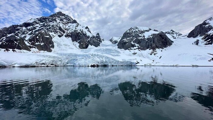 Une photo de montagne enneigées le long d'une étendue d'eau.