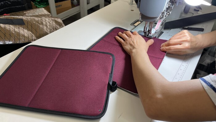 Un employé qui cout un sac à vélo.
