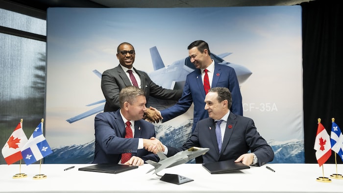 Quatre hommes d'affaires en complet veston-cravate se serrent la main.