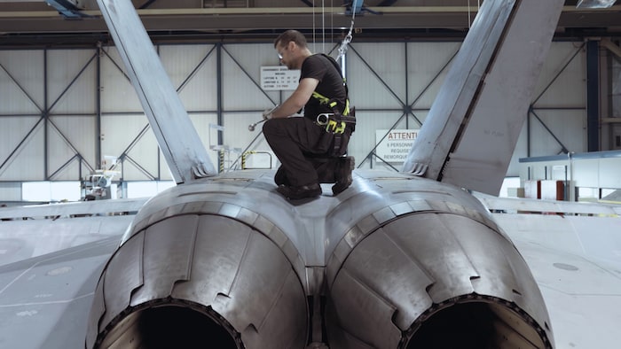 Un employé est en train de faire la maintenance d'un avion dans une usine.