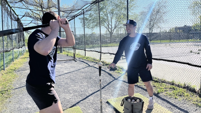 Deux joueurs s'entraînent à frapper ensemble à l'aide d'un « tee ball ».