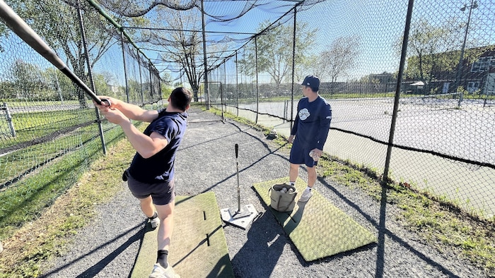 Takuto Kanno aide son capitaine à frapper des balles dans une cage d'entraînement drummondvilloise.