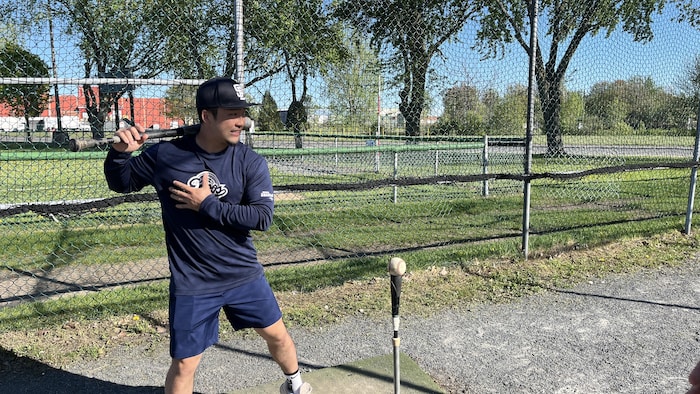 Takuto Kanno s'apprête à frapper la balle dans une cage d'entraînement.