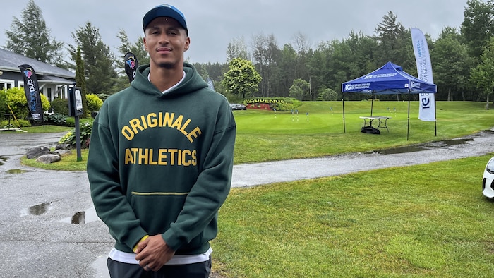 Le joueur de football Benjamin St-Juste regarde la caméra et sourit, sur le terrain de golf.