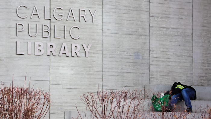 Un homme couché dans un escalier à l'extérieur de la bibliothèque centrale de Calgary.