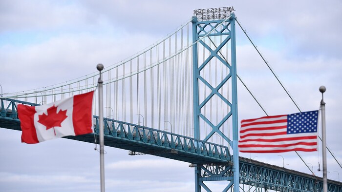 علم كندا (إلى اليسار) وعلم الولايات المتحدة يرفرفان قرب جسر ’’أمباسادور‘‘ الذي يربط مدينة ويندسور الكندية بمدينة ديترويت الأميركية والذي يُعتبر أهمّ ممرّ تجاري بين البلديْن.