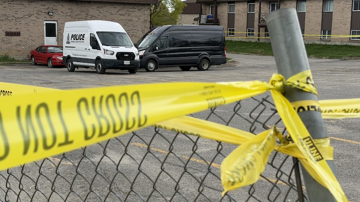 Un ruban de police et des véhicules.