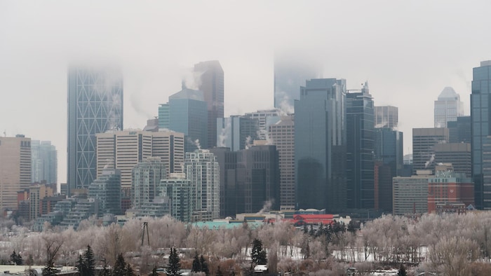 Édifice du centre-ville de Calgary partiellement couvert de brouillard. De la fumée s'échappe de plusieurs d'entre eux. 10 janvier 2024.