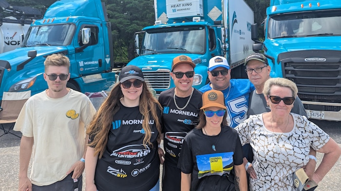Des gens posent devant un camion.