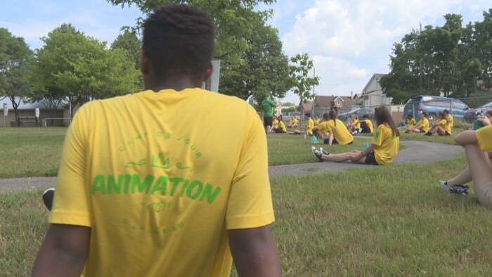 Animateurs de camps de jour assis dans l'herbe lors d'une formation dans un parc.