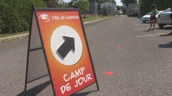 Affiche indiquant l'entrée des camps de jour dans un stationnement.