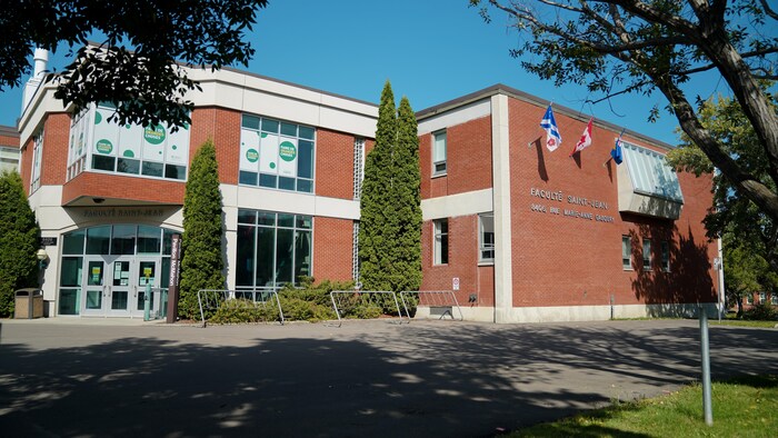 Devant du bâtiment, un jour ensoleillé d'été avec des zones d'ombres. On peut lire l'inscription Faculté Saint-Jean sur le côté.