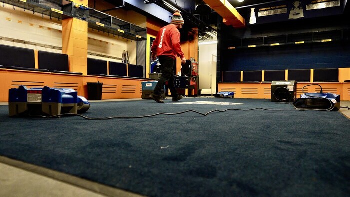 Un homme dans un vestiaire avec des séchoirs.
