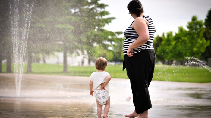 Catherine Voyer-Léger et Charlie sont dans un parc, à proximité d'une structure avec des jets d'eau.