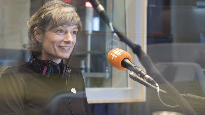 Céline Huyghebaert, devant un micro, sourit.