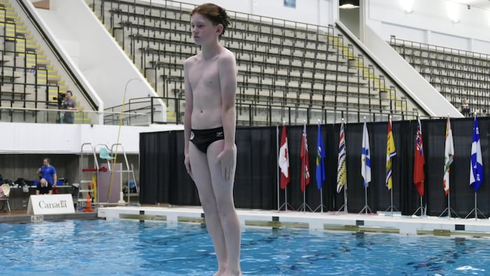Un jeune plongeur se prépare à sauter du tremplin.