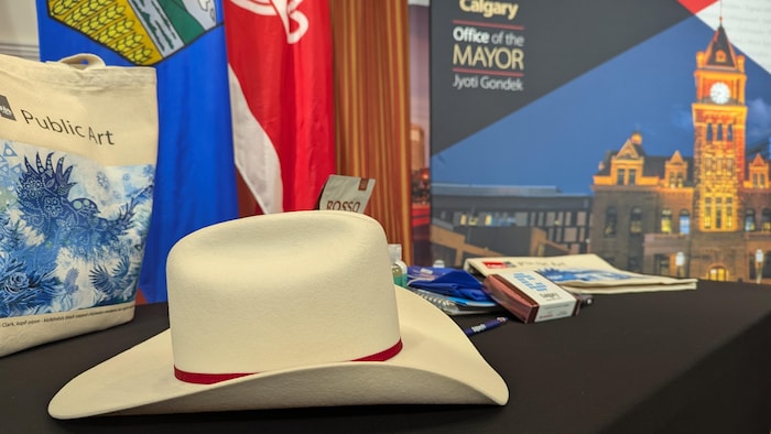 Un chapeau blanc est posé sur une table avec un paquet de café, des chocolats et un sac en tissu.