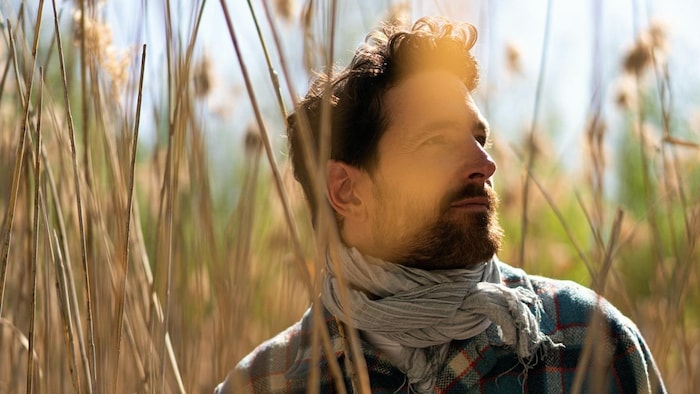 L'auteur-compositeur-interprète Charles-Antoine Gosselin se tient dans un champ de blé.