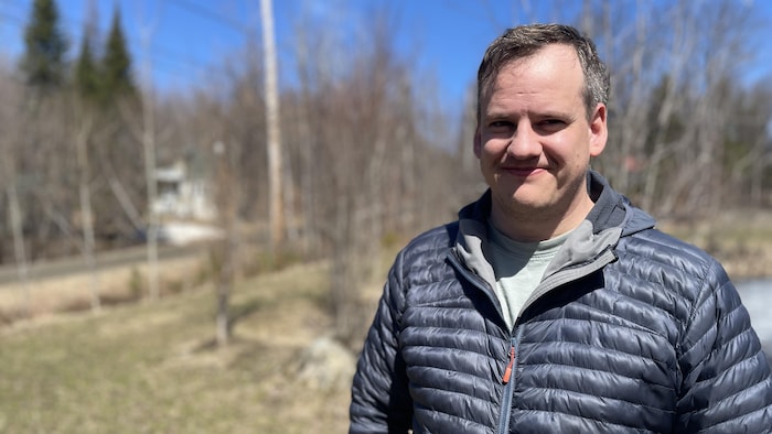 Un homme sourit en regardant la caméra. 