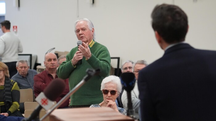 Une personne, tenant un micro, pose une question à Charles Milliard.