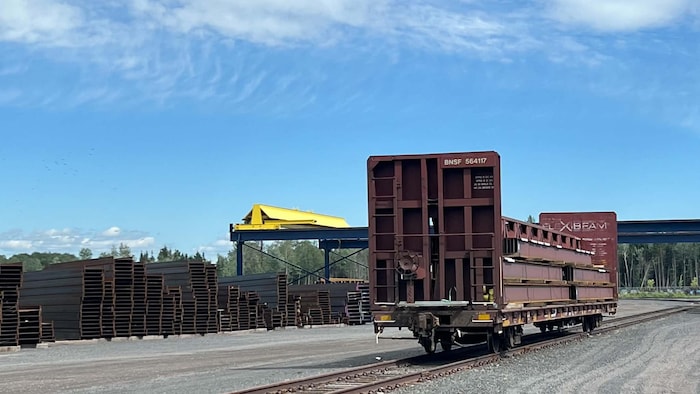 Un wagon sur un chemin de fer près de pièces d'acier.