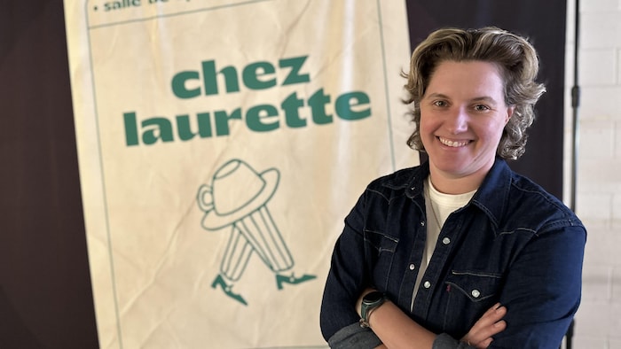 Une femme souriante qui pose devant une affiche de Chez Laurette.