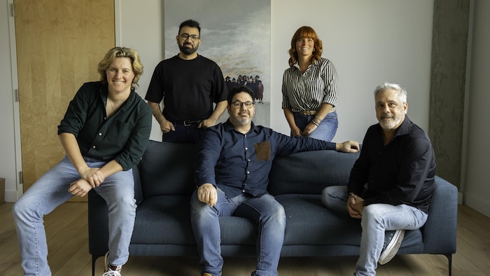 Cinq personnes qui posent assises ou autour d'un fauteuil.