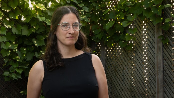 Une femme souriante qui pose à l'extérieur.