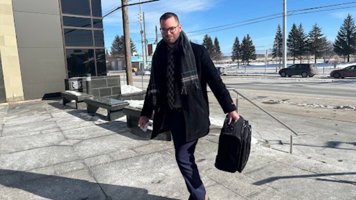 Chris Ryan, une mallette à la main, sur les marches du palais de justice de Moncton.