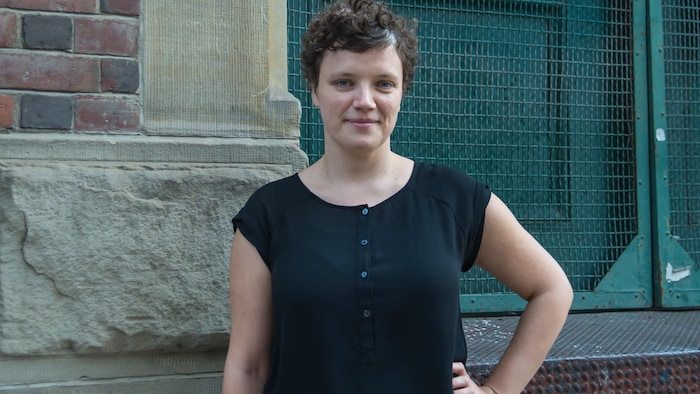 Une femme avec une main sur la hanche face à l'objectif.