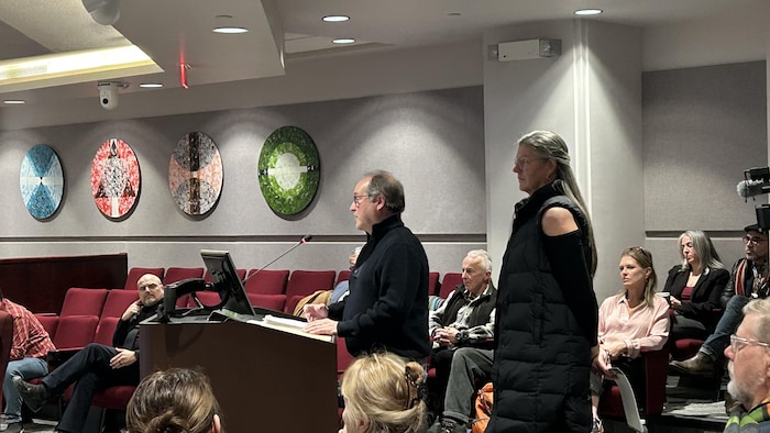 Deux personnes devant les conseillers municipaux. 