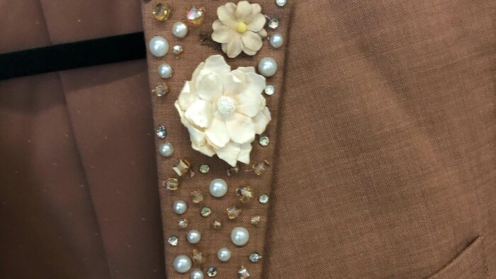 Un collet de veston avec plusieurs petites fleurs et autres bijoux.
