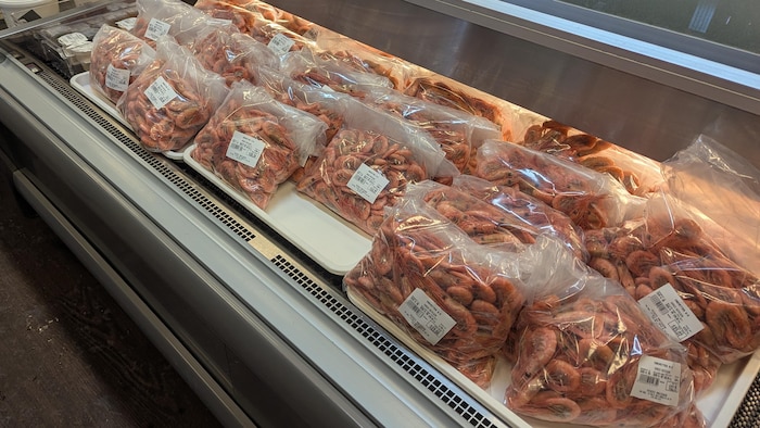 Des crevettes emballées dans un réfrigérateur ouvert.