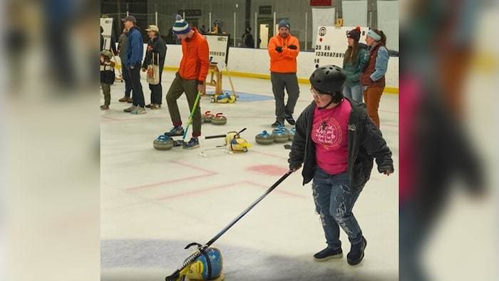 Une femme tente de faire avancer sa dinde sur la glace, tandis que d'autres joueurs tentent de faire la même chose, derrière elle.