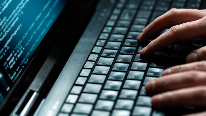 Des mains tapent sur un clavier d'ordinateur.