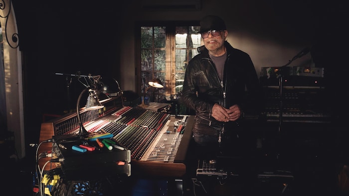 Un homme souriant, debout dans un studio d'enregistrement.
