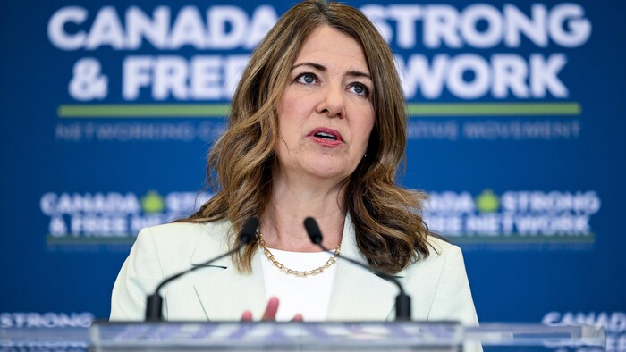 La première ministre de l'Alberta, Danielle Smith, répond aux journalistes devant une bannière du Canada Strong and Free Network à Ottawa le 8 mai 2026.