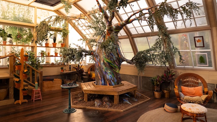 Un grand arbre coloré dans un décor rempli de plantes.