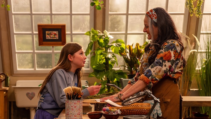 Une jeune fille et une femme qui discutent dans un décor rempli de plantes.