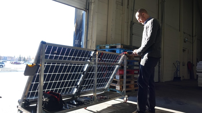 Darren Dunfield tient un boîtier lui servant à mesurer l'efficacité d'un panneau solaire.