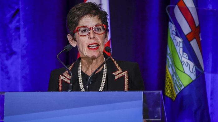 Deborah Yedlin parle à un lutrin devant un drapeau de l'Alberta le 15 décembre 2022 à Calgary. 
